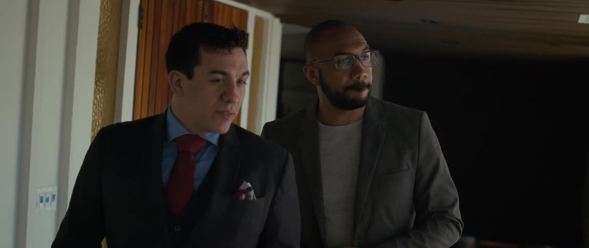 Two men walking through a building as one talks and the other listens