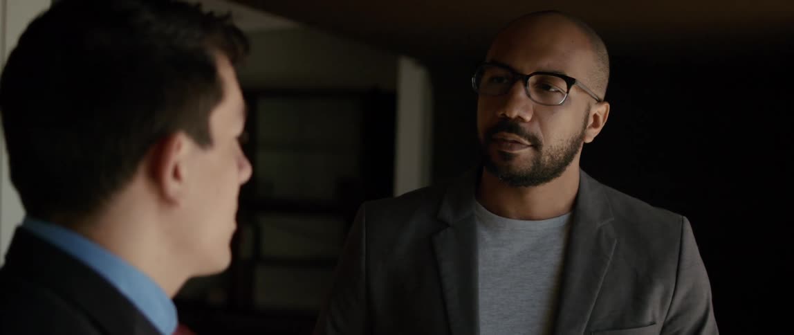 Two men are talking and one man nods his head as he listens to the other man speak
