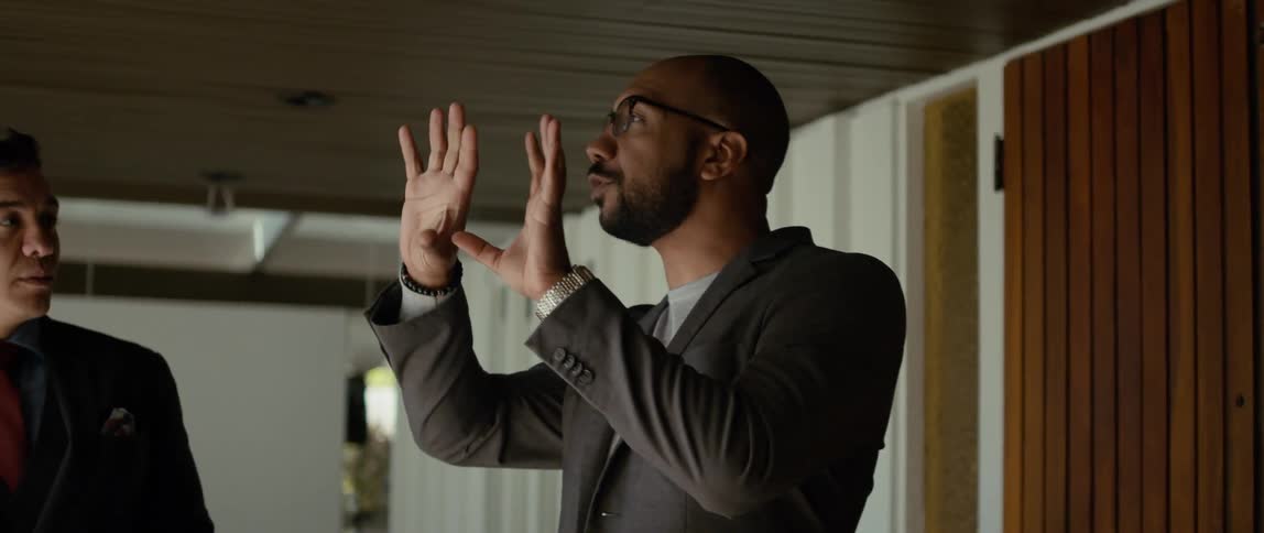 Two men are standing together and one man is using his hands as he talks
