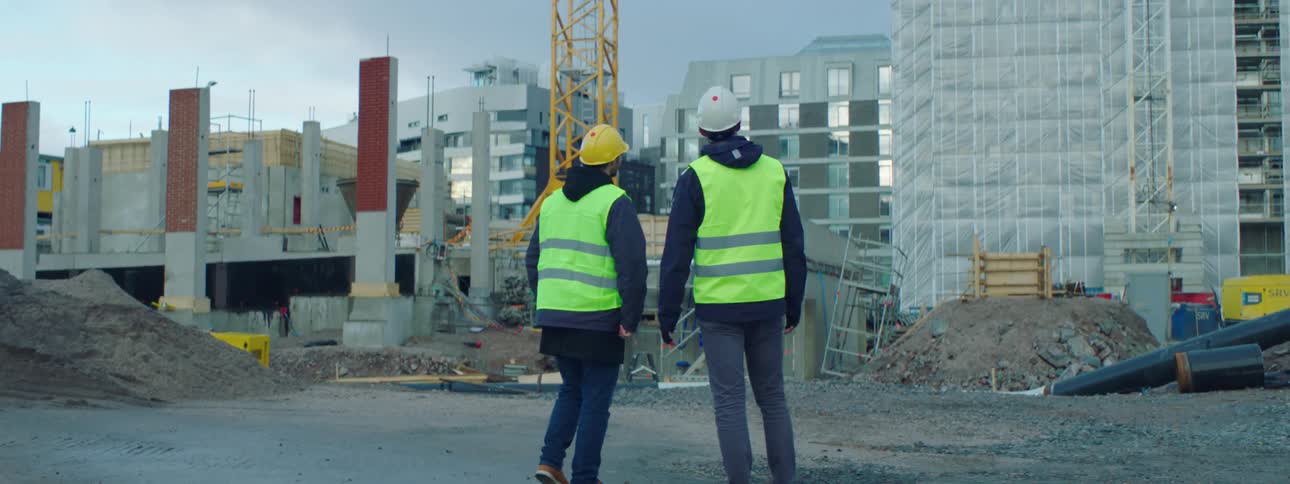 Construction workers shake hands on a job site before looking at buildings