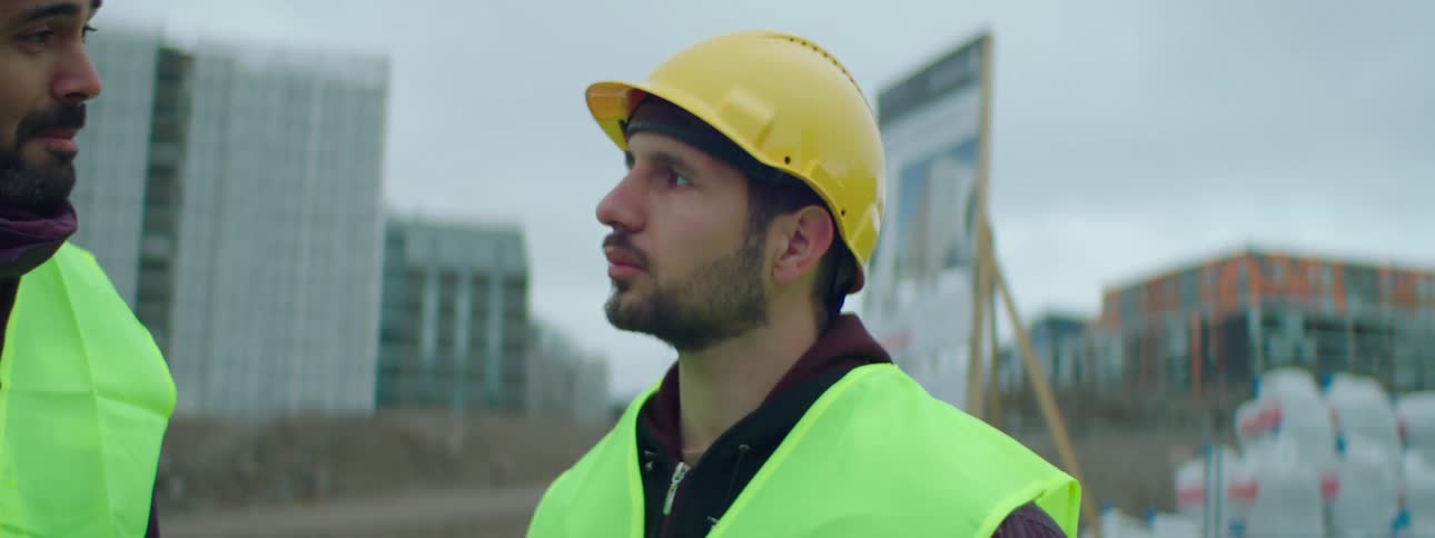 Two construction workers stand at work site in town holding a discussion