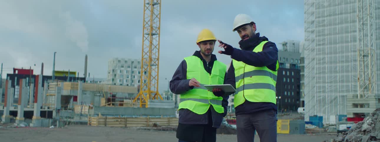 Two construction workers talk on site