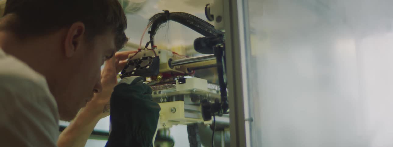 A man is using a tool to work on the inside of a machine