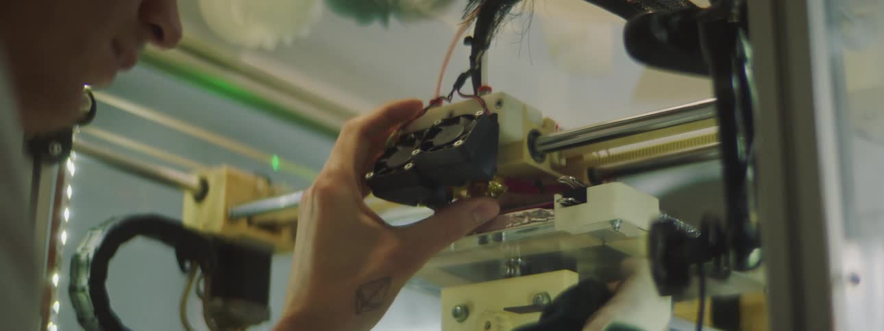 Man wearing protective gloves cleaning the extruder of a 3d printer