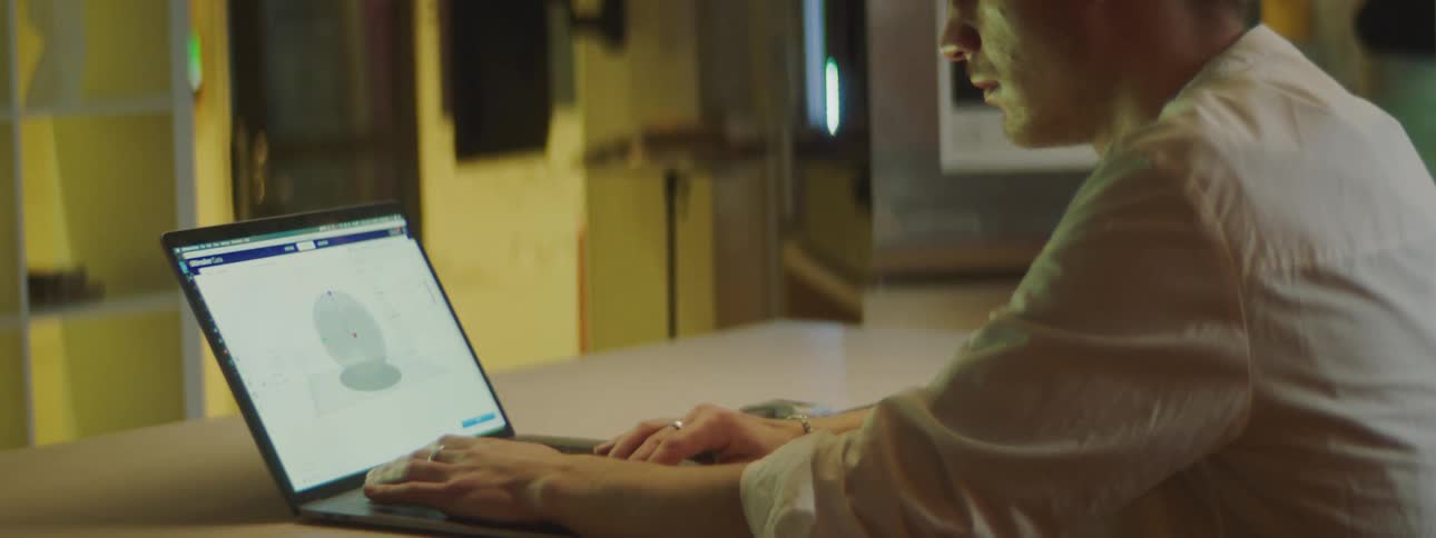 A man is sitting at his desk and typing on a laptop