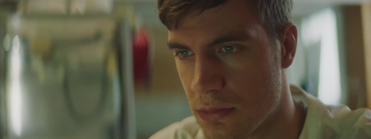 A man is sitting at a desk and looking at a screen