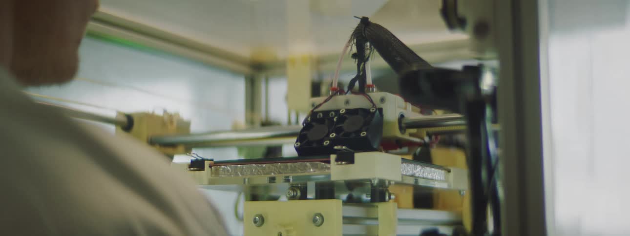 A man watches a 3d printer as it prints