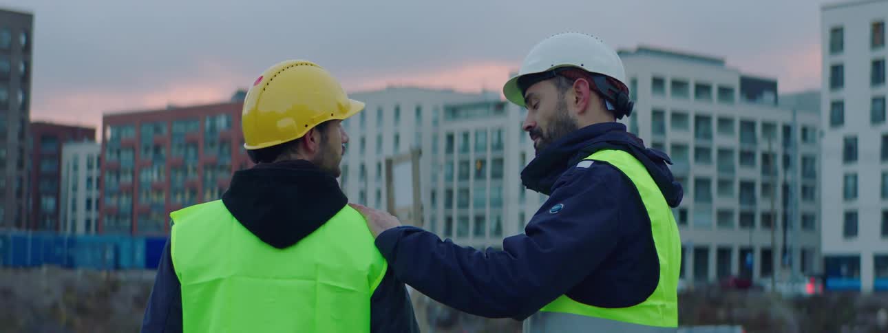 A construction worker touches a colleagues shoulder before they leave a job site