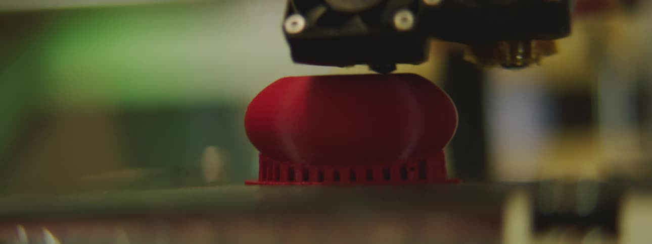 3d printer creating an object out of red plastic