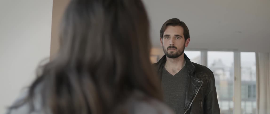 A brown haired woman is talking to a bearded man