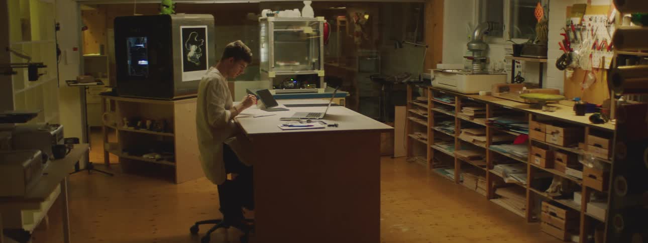 A man sits at a desk in a lab and works