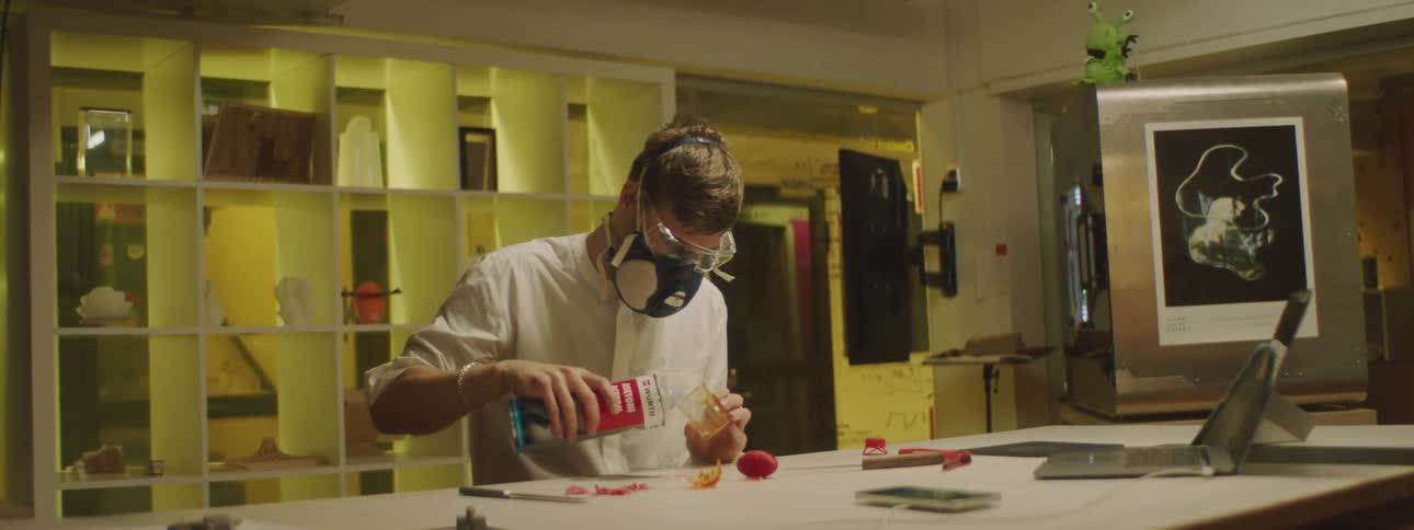 Man wearing protective goggles and air filtration mask filling a beaker on a laboratory