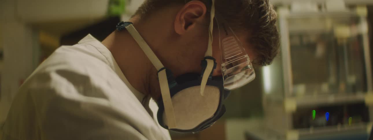 A man is wearing goggles and working in a lab