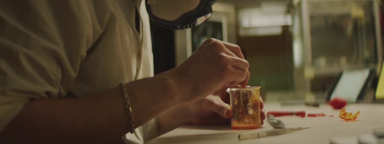 Male stirring orange liquid in a beaker during an experiment
