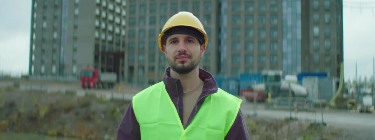 Construction worker posing in front of building site