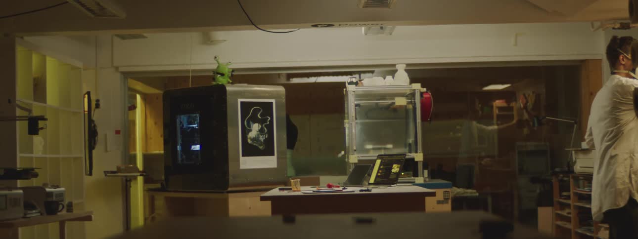 A man in a lab walks away from his desk and those goes back and starts digging in a glass