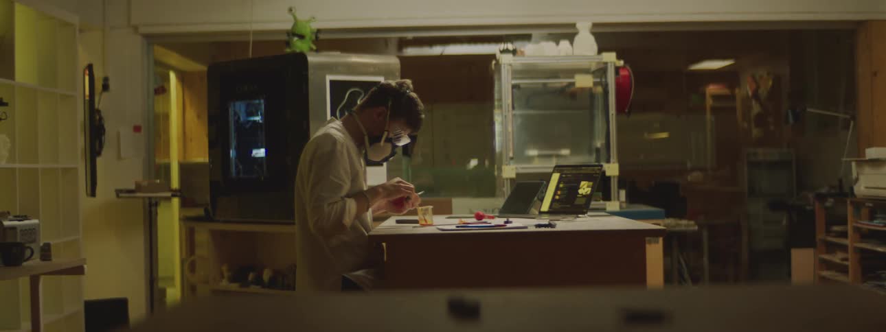 Man wearing safety glasses and air filtration mask cuts smalls pieces of fruit with pliers on a beaker in a laboratory