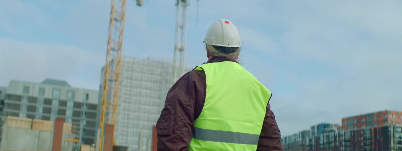 Older worker standing on construction site gives guiding gestures