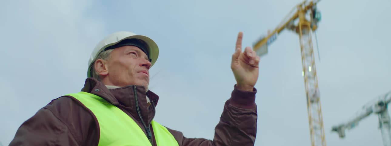 A construction worker signals by moving his finger and hand in a circle