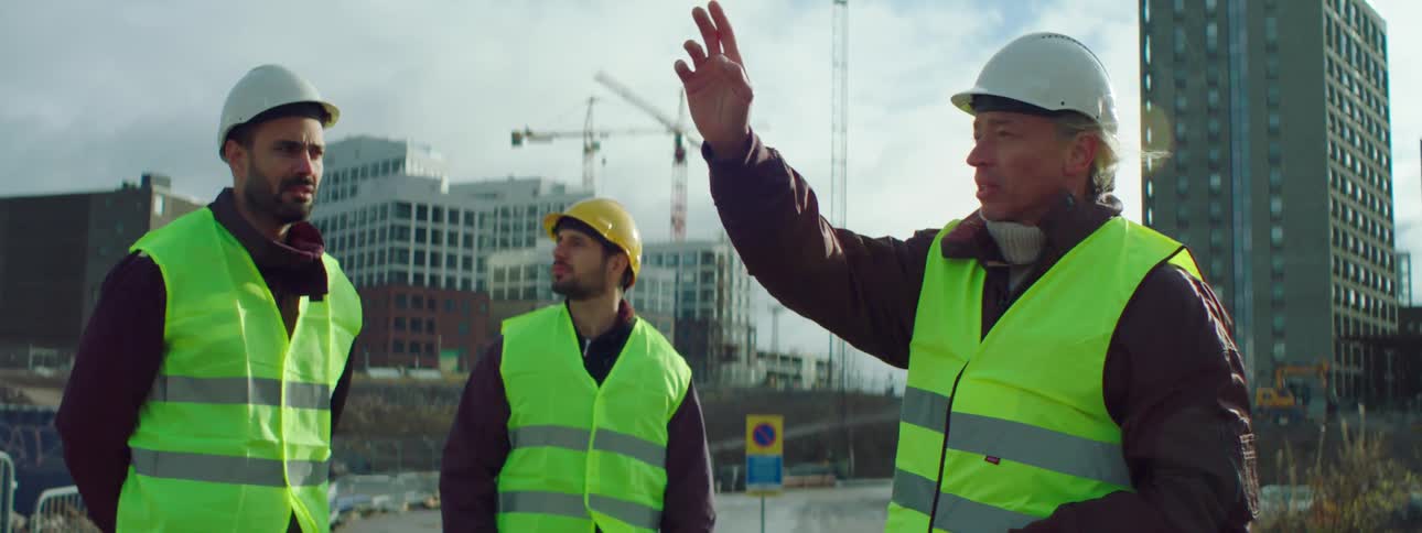 Construction workers are outdoor talking and planning at a construction site