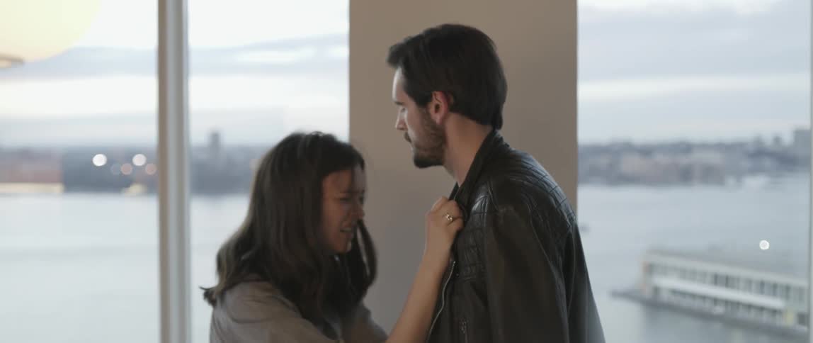 A man hugs a woman and looks out the window