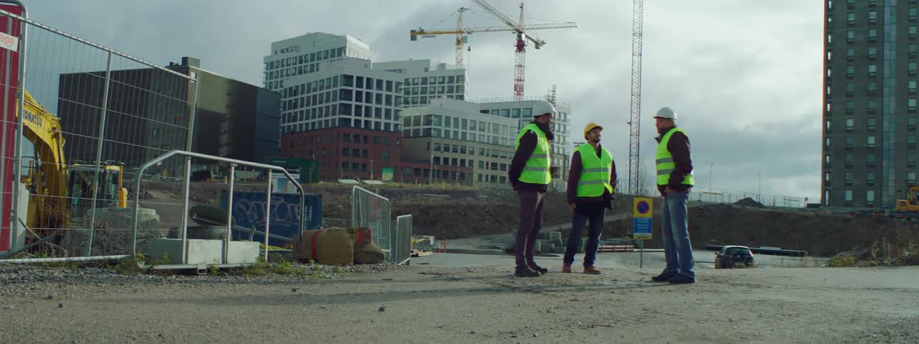 A man on a construction site shakes hands with two other men