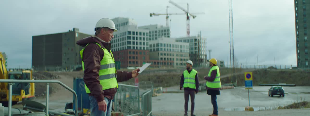 A construction worker uses a tablet for a video call at a work site