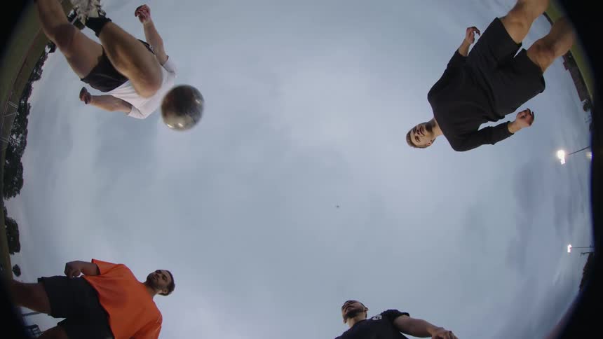 Four male soccer players kicking a ball back and forth while gathered in a circle