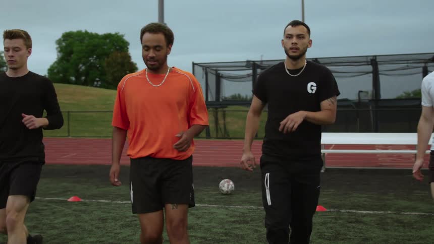 Four men stretch their legs in unison in a stadium