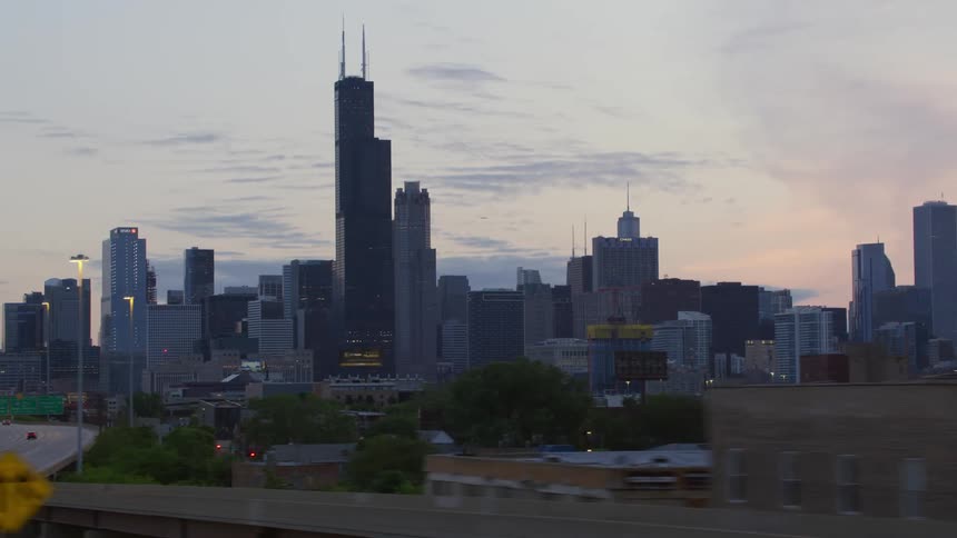 Skyscrapers loom over a freeway in a metropolis in the evening