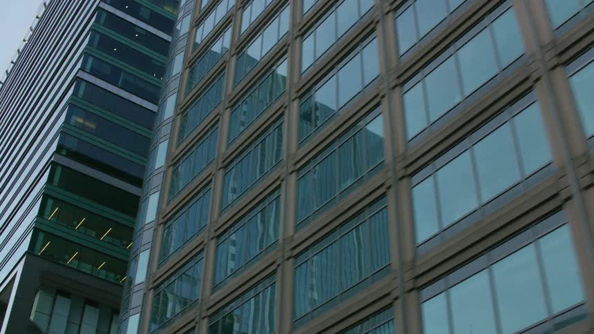 Nearby buildings and the sky reflect on the windows of downtown buildings and skyscrapers