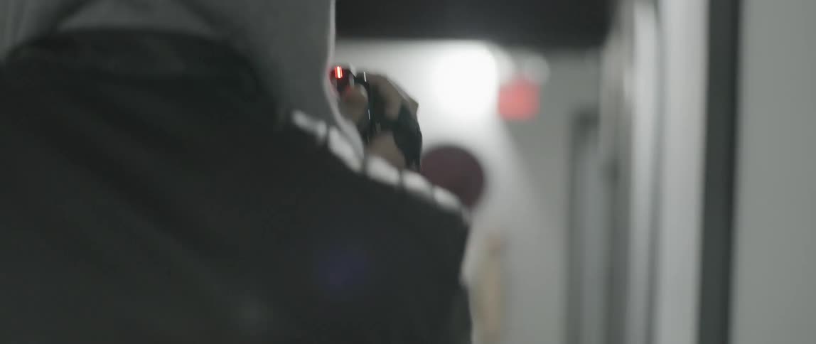 A man following a woman and filming her as she walks through a hallway