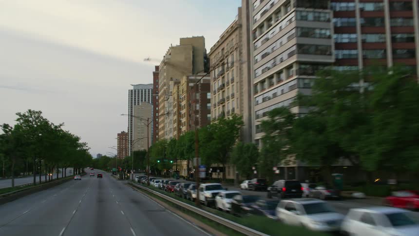 Traveling past city buildings where buses taxis and cars are stopped