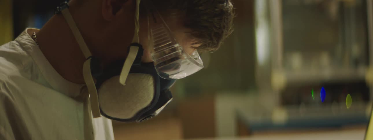 A man wears goggles and a gas mask while working in a lab