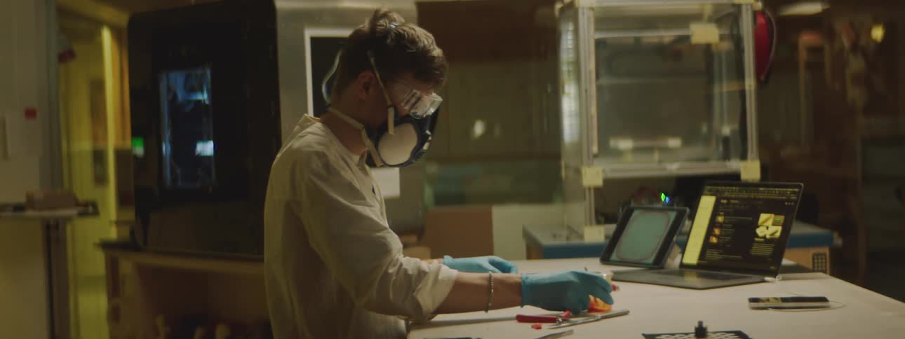 Man wearing protective goggles and air filtration mask puts on blue latex gloves to work on a laboratory