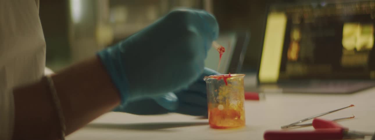 A man mixes a red polymer in a beaker and applies to a 3d printed product