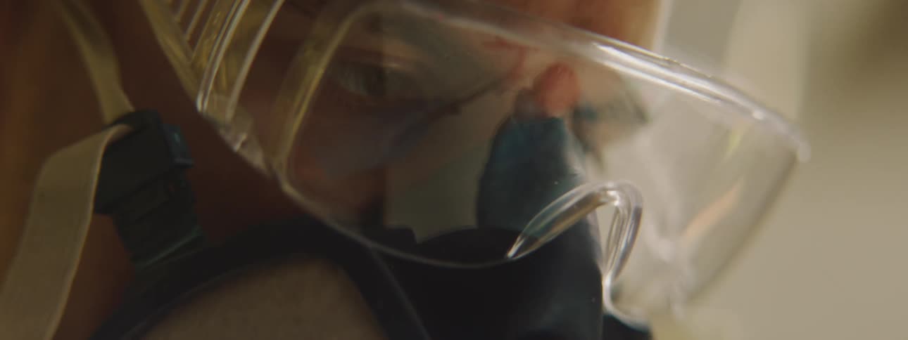 Closer up of the eyes of a working man wearing safety glasses and air filtration mask