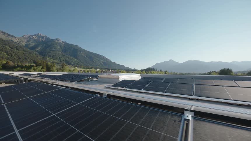 Solar panels on a rooftop near hills and mountains and a small town