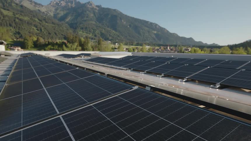 Solar panels sit in long rows below tall hills