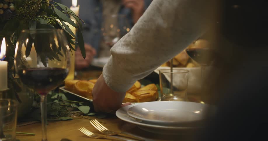 A man setting a plate of food on a dinner table