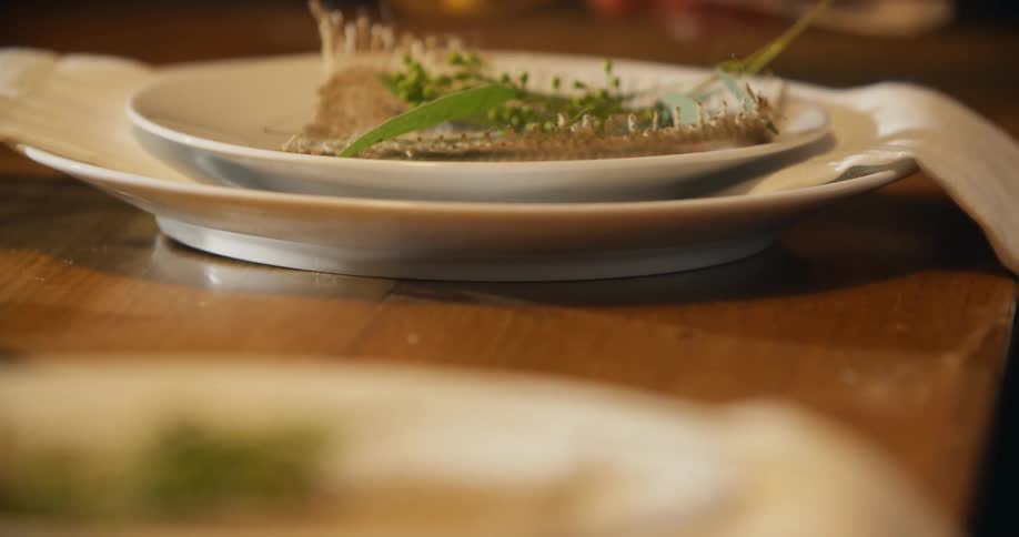 A woman setting floral decorations on a dinner plate