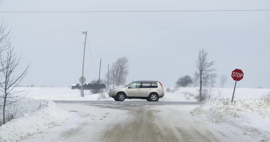 Someone exiting a vehicle at an intersection in a rural area covered in snow