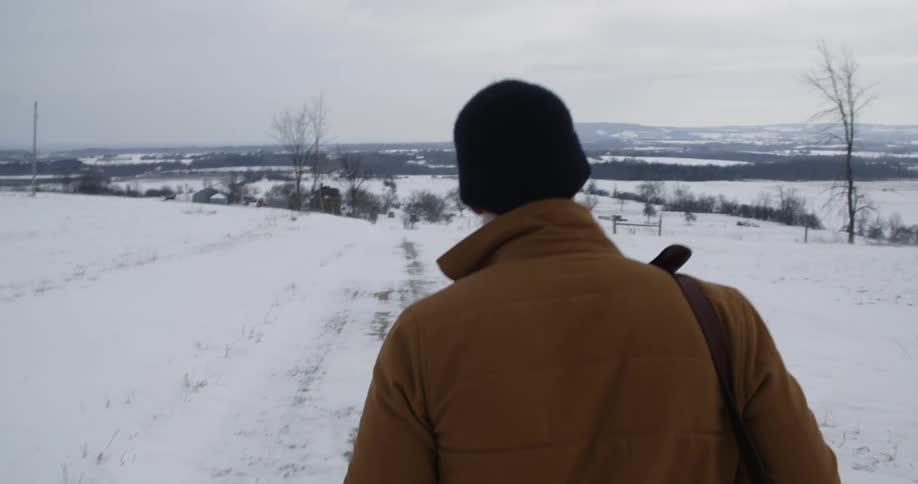 A man is walking along a snow covered area