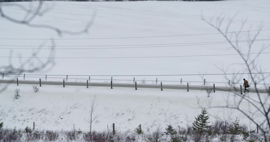 A man walks down a country road in winter