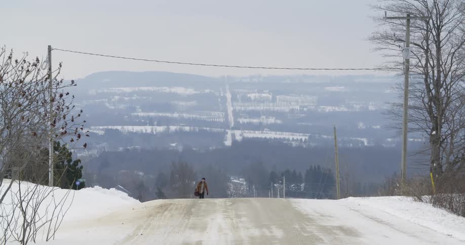 A man is walking up a snow covered road