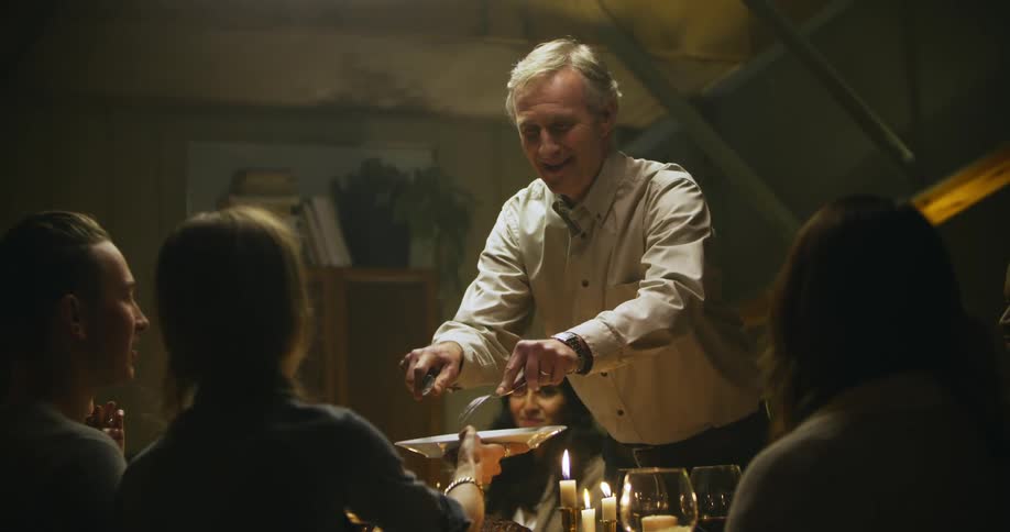 A man slices meat and puts it on a woman's plate