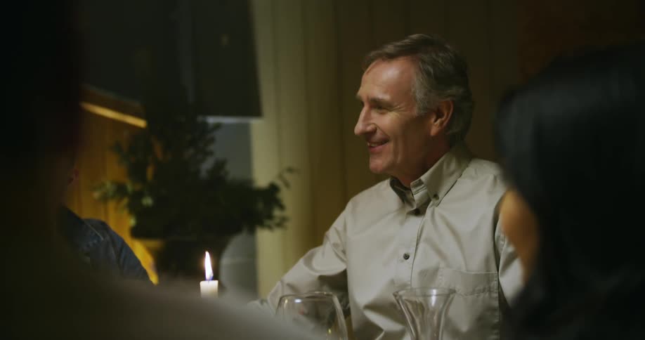A man converses with his family at the dinner table