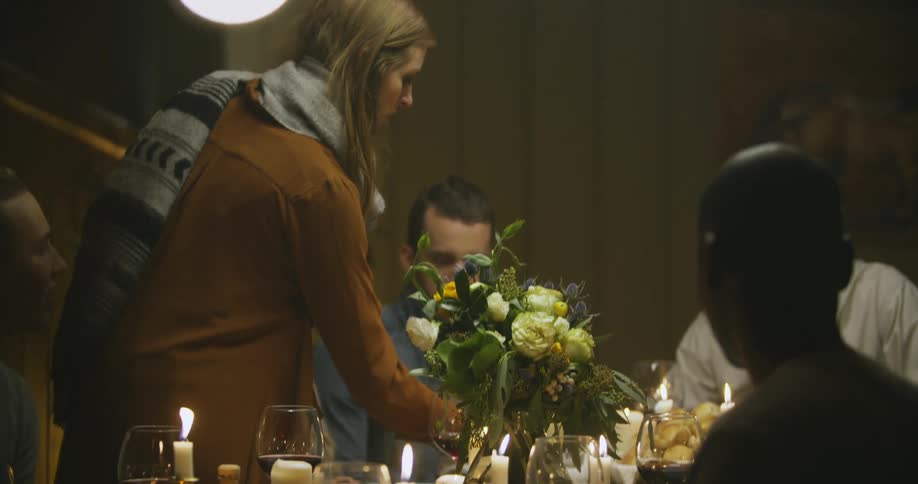 A woman sets down a gravy boat on a table