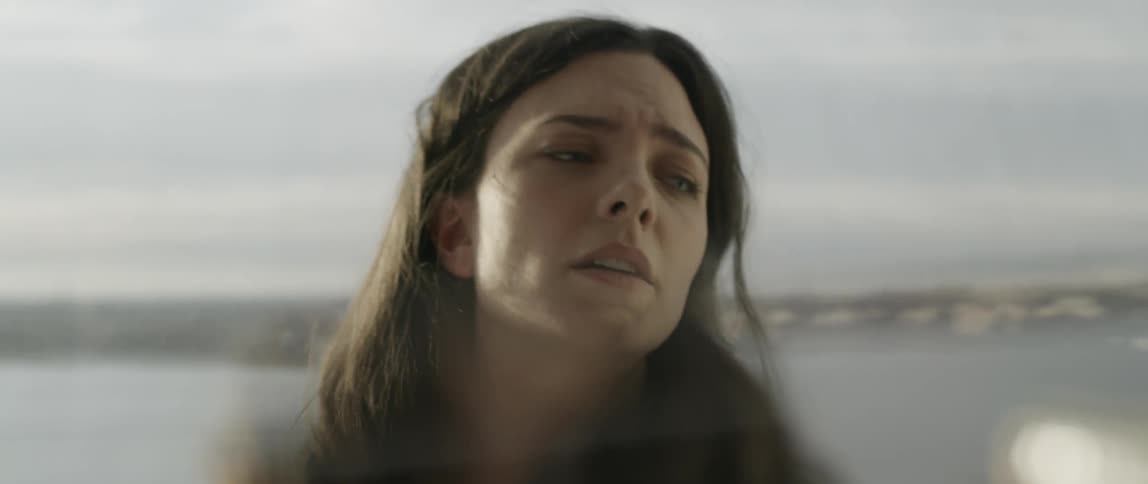 A dark haired woman closes her eyes and then walks away