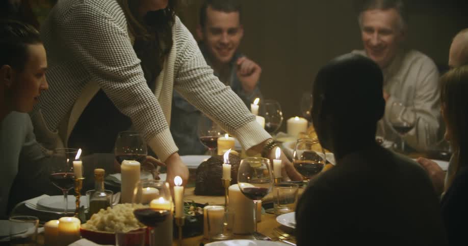 A woman setting a roast on a dinner table